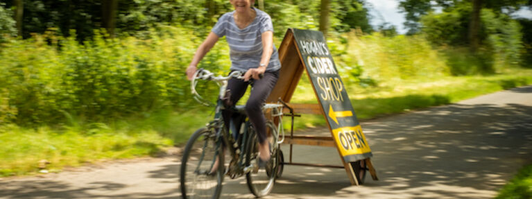 Jane moving Hogan's Cider shop sign by bicycle