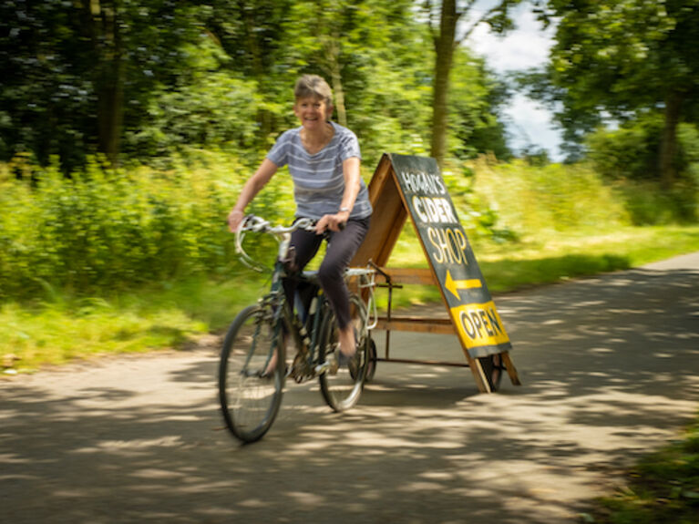 Jane moving Hogan's Cider shop sign by bicycle